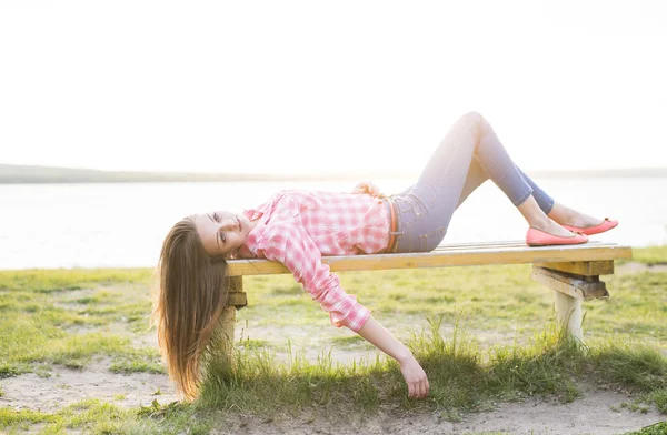 Молодая женщина лежит на деревянной скамейке — стоковое фото