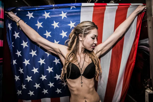 Mujer sosteniendo en las manos gran bandera americana — Foto de Stock