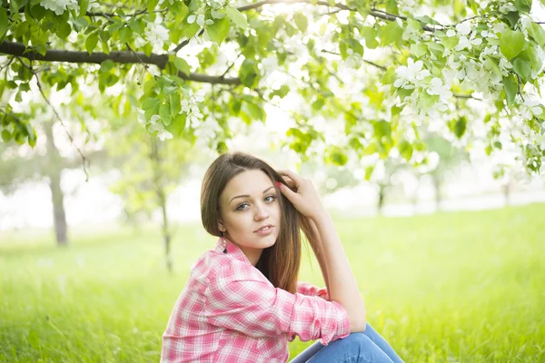 Chica sentado bajo blomming árbol —  Fotos de Stock