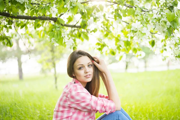 Girl sitting under blomming tree Royalty Free Stock Photos