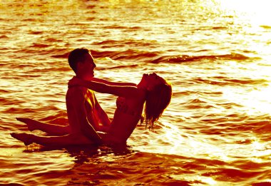 Gün batımında suda duran iki genç yetişkin aşıklar 