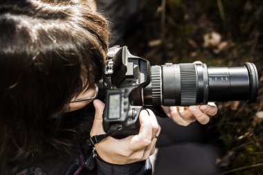 yukarı görünüm. Nehirde suya karşı bir şey hedefleyen açık flaşlı kameraile kadın-fotoğrafçı