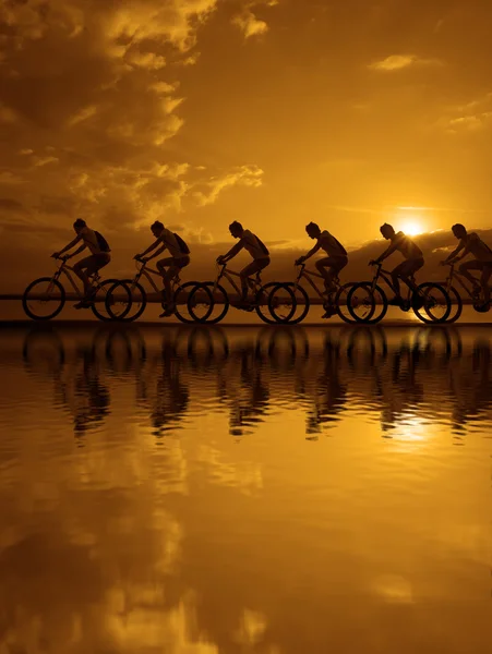 Silhouettes sombres d'amis sportifs sur des vélos — Photo