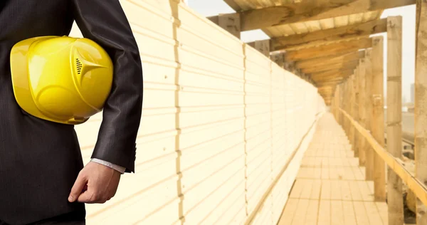 Рука инженера держит желтый шлем — стоковое фото
