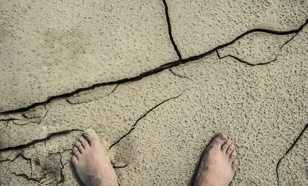 Fötterna på torra spruckna marken — Stockfoto