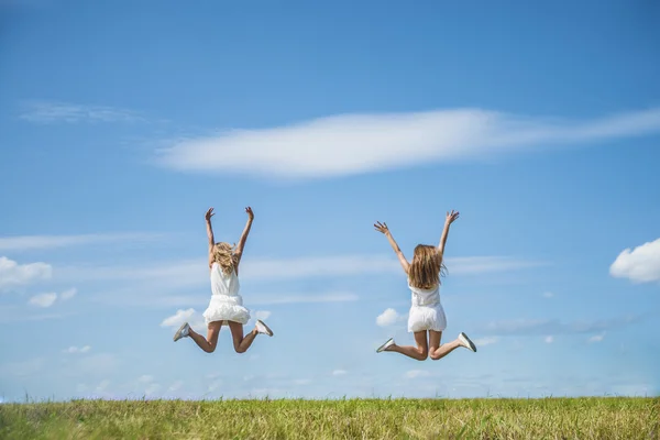 Duas mulheres com as mãos para cima pulando . — Fotografia de Stock