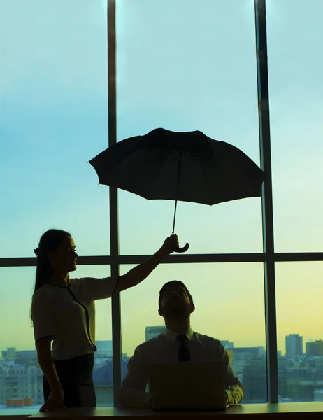 woman holding umbrella over  boss