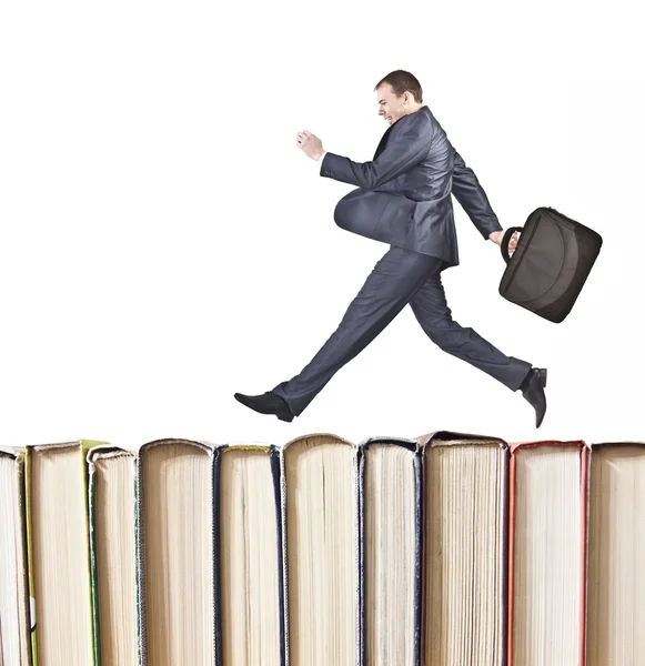 Businessman jumping over books — Stock Photo, Image