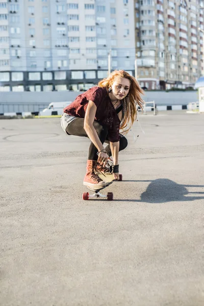 Beautiful young woman on  skateboard \ against urban street background .
