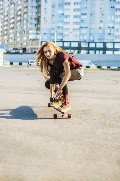 Beautiful young woman on  skateboard \ against urban street background .