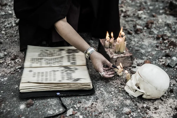 Heks en schedel met open magische boek — Stockfoto