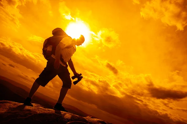 Turista con mochila contra atardecer cielo — Foto de Stock