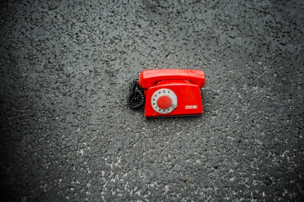 vintage red phone on black asphalt
