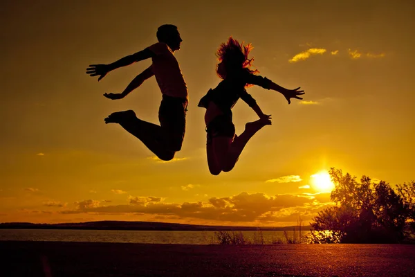 Silhouette Couple Man Woman Jumping Beach Sunset Cloudy Sky Orange — Stock Photo, Image