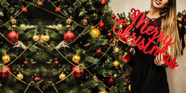 Mujer sosteniendo feliz navidad palabras —  Fotos de Stock