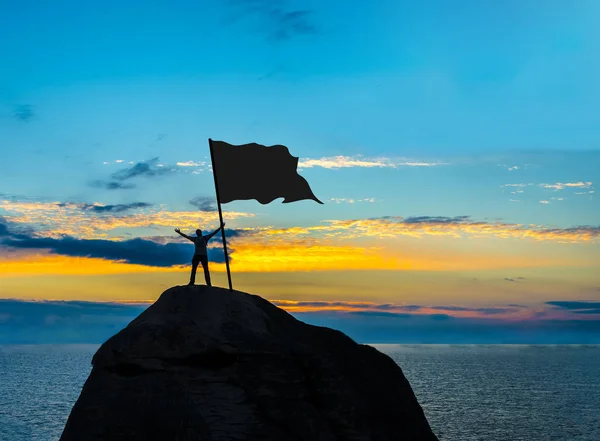 Sylwetka człowieka z flagą na szczycie góry — Zdjęcie stockowe