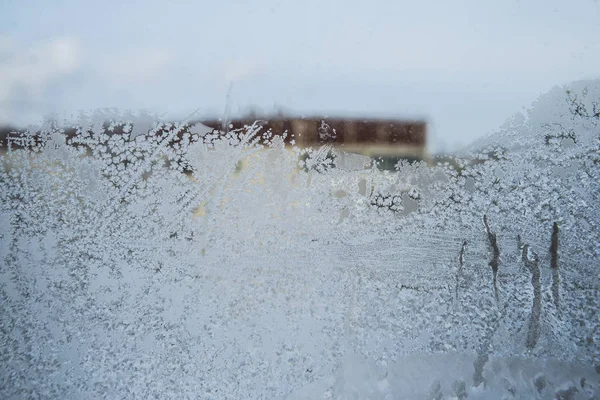 Снежинки и морозы на оконном стекле — стоковое фото