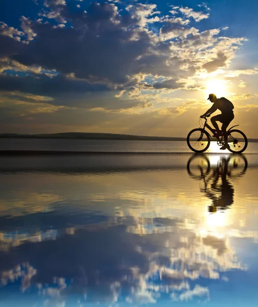 Silhouette Maschili Bicicletta Con Riflesso Acqua Sullo Sfondo Del Tramonto — Foto Stock