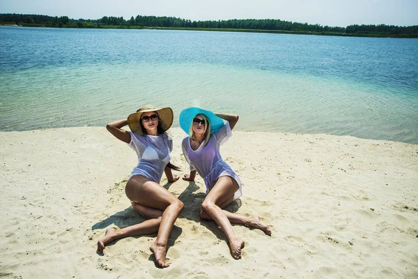 Women sitting on white hot sand — Stock Photo, Image