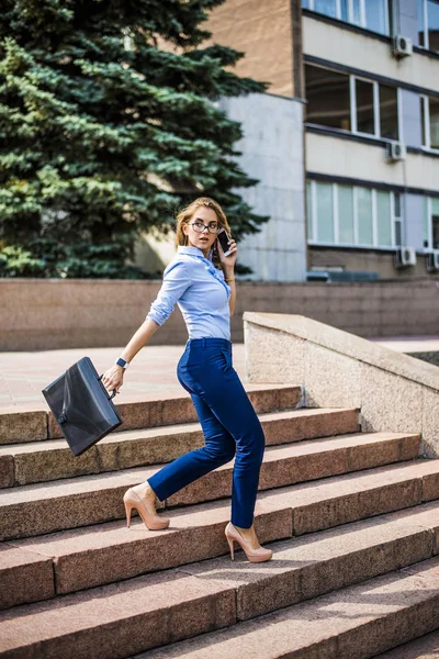 Young beautiful businesswoman walking  down the stairs with brief case