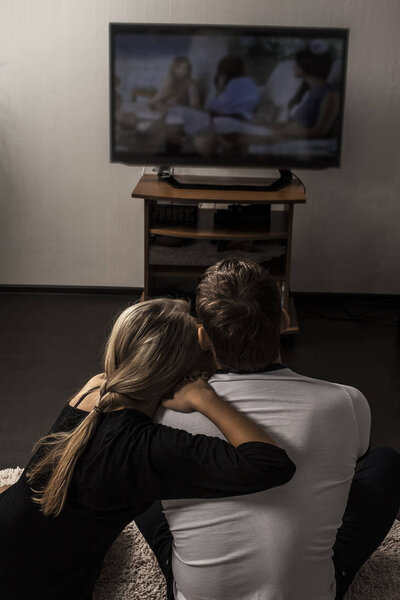 пара сидит на диване смотреть телевизор

