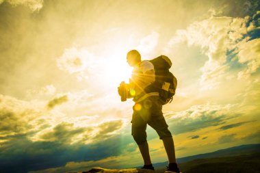 Fotoğrafçı güneşli bulutlu gökyüzü üzerinde dürbün ile izliyor 