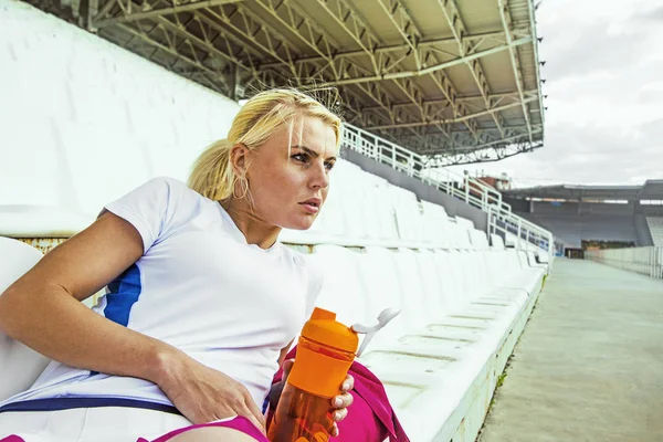 Stadyum üzerinde siting ve içme kadın — Stok fotoğraf