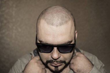 Hipster siyah güneş poising adam sakallı. Koyu gri duvar kağıdı arka plan üzerinde kalın adam.