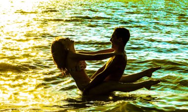 Gün batımında suda duran iki genç yetişkin aşıklar 