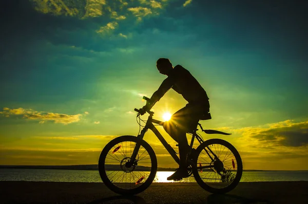 Homem de bicicleta no pôr do sol . — Fotografia de Stock