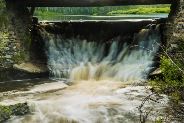 Wasserfall unter hölzerner Transportbrücke. — Stockfoto