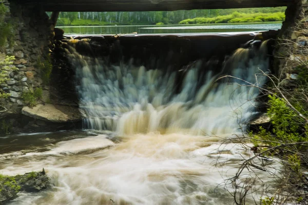 Wasserfall unter hölzerner Transportbrücke — Stockfoto