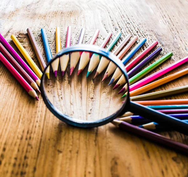 Pencils under magnifying glass — Stock Photo, Image