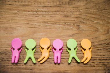 ahşap masa arka plan üzerinde renkli plastik insanlar rakamlar. Eller yukarı.