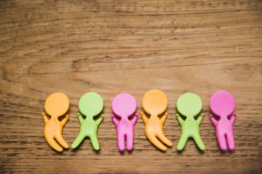 ahşap masa arka plan üzerinde renkli plastik insanlar rakamlar. Eller yukarı.