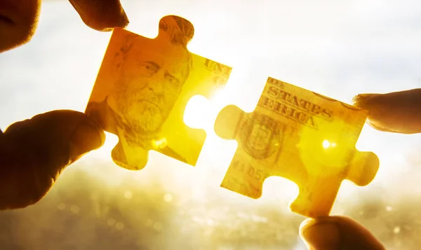 Hand and two money puzzle pieces from  dollar bill  isolated on white background