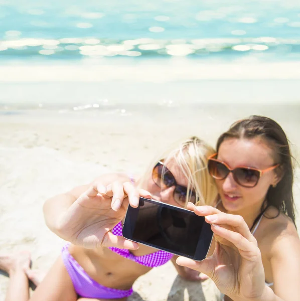 Две Улыбающиеся Девушки Пляже Делают Селфи Смартфоном Фоне Синей Воды — стоковое фото