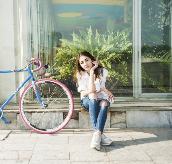 Дівчина сидить біля старовинного велосипеда — стокове фото