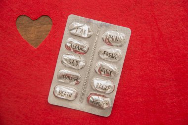 Kırmızı kalp arka plan ve boş hap blister ile kelimeler - şişman, boyalı ağrı, yalnız, ucube, üzgün, çirkin, kabartma, ölüm, kaçış. Sağlık arka plan ve fikir. 