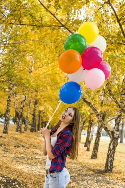 Güzel kız, portresi giyinmiş gündelik elbise tarzı, sarı orman Park balonlar ile gülümseyen 