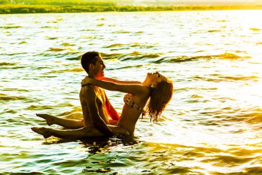 Gün batımında suda duran iki genç yetişkin aşıklar 