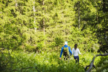 Vahşi dağ ormanında bir çift turist sırt çantalı. arka görünümü. Aktif turizm. Doğada seyahat eden kadın ve erkek. yazıt veya nesneler için boş kopyalama alanı. yaz sezonu 