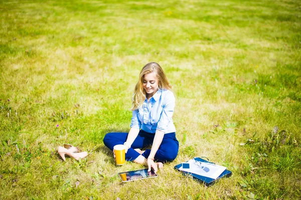여자는 커피를 마시고 태블릿을 신선한 잔디에 — 스톡 사진
