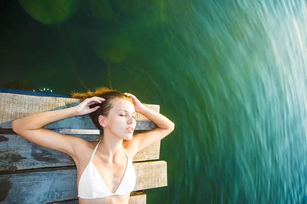 Menina deitada no cais de madeira — Fotografia de Stock