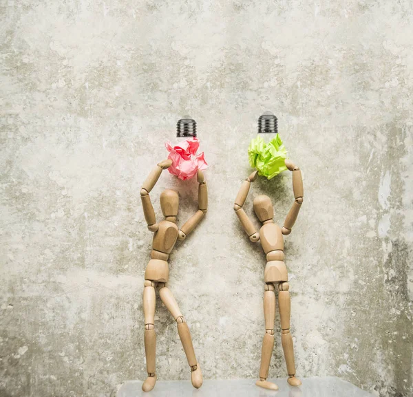 Ampul lambalar ile iki ahşap rakamlar. Beton duvar arka plan karşı ahşap rakamlar. 