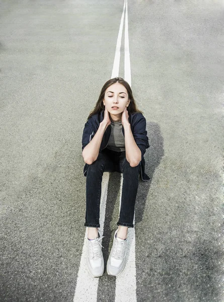 Девушка, сидящая на середине дороги — стоковое фото