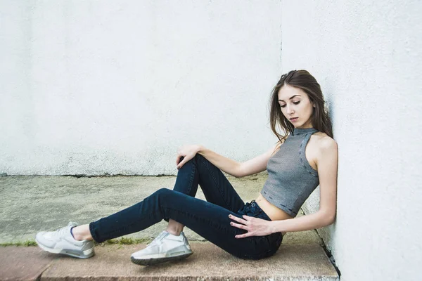 Mujer sentada cerca de pared gris . —  Fotos de Stock
