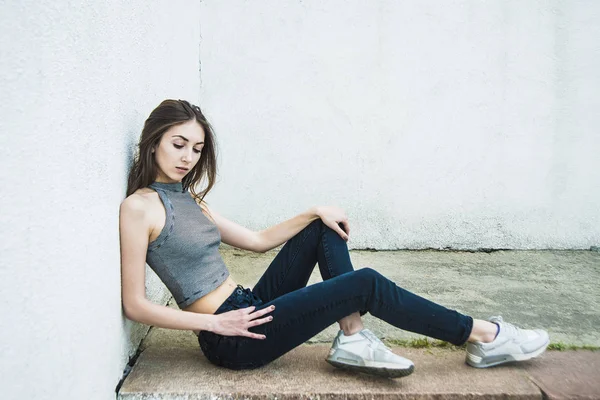 Mujer sentada cerca de pared gris . —  Fotos de Stock