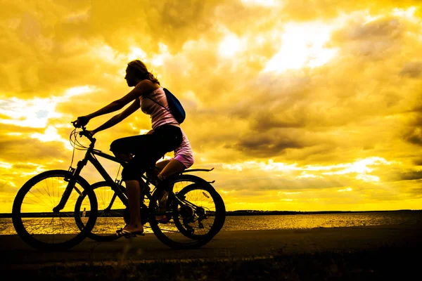 空の空間 夕日に自転車でスポーティな友人 海岸沿いの乗馬の自転車 自然バック グラウンドでスポーツ — ストック写真