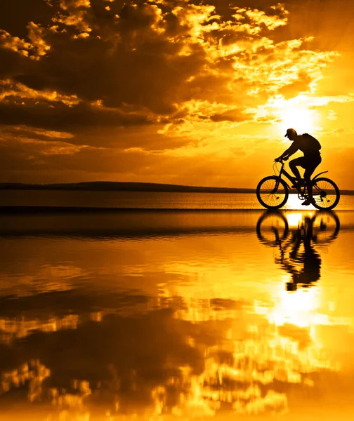 Férfi Sziluettek Kerékpár Tükörképe Vízben Naplemente Háttér — Stock Fotó
